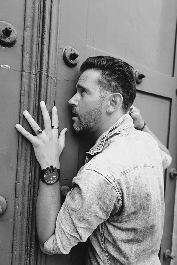 A man leaning against a door with his hands on the door.