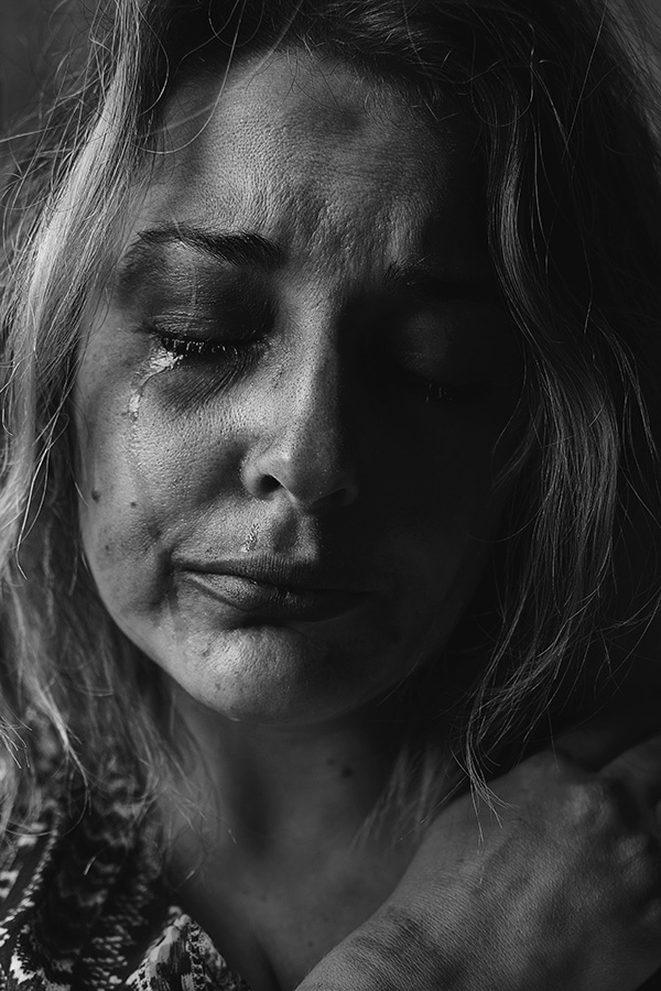 A woman with a teary face in a black and white photo.