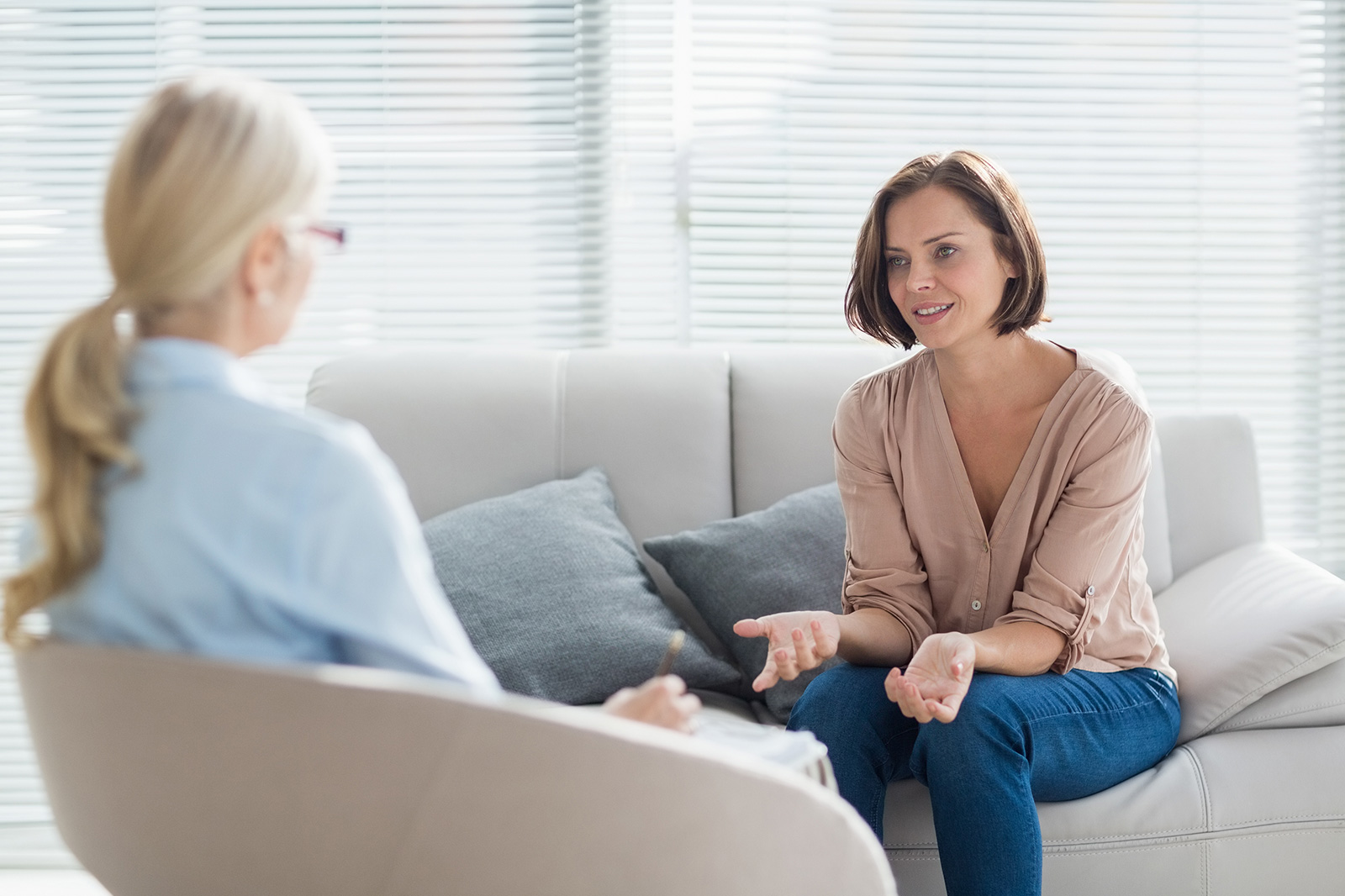 A female patient discusses treatments for depression with her female doctor in a bright, airy office.