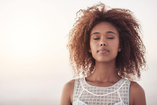 A female has eyes closed in a peaceful setting and looks zen, perhaps showing how SAINT TMS therapy helped with her depression