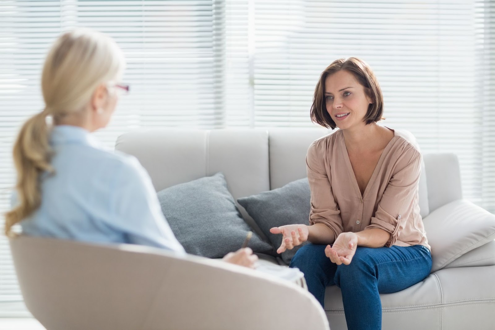Two women engaged in a conversation about depression and suicidal ideation while sitting on a couch