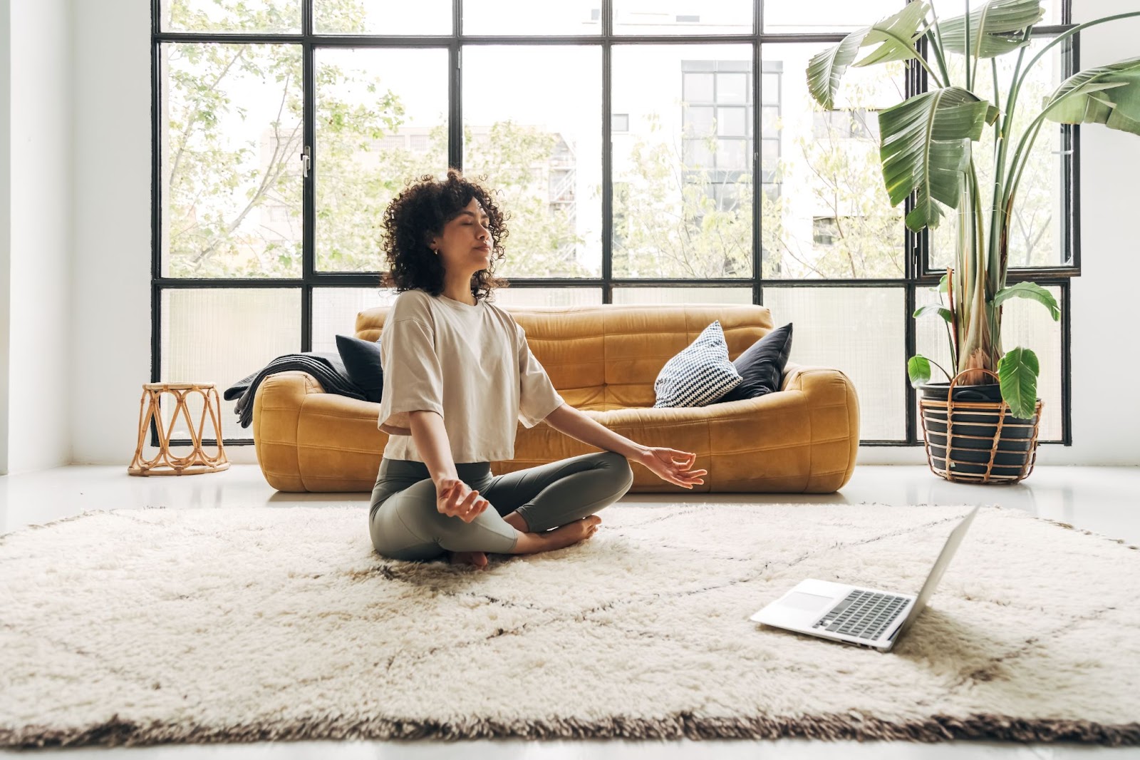 Woman meditating on a rug, finding peace amid anxiety and TMS therapy
