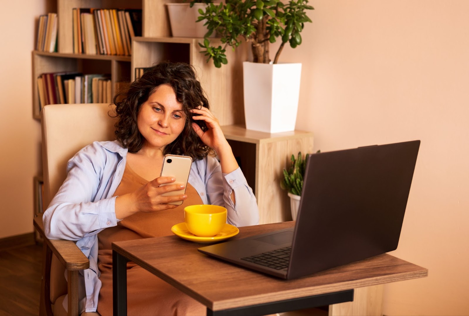 A woman sitting at a desk with a laptop and a cup of coffee, receiving TMS therapy for ADHD with ADHD medication nearby.