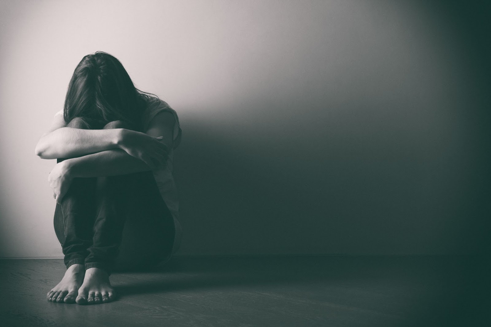 A woman sitting on the floor with her hands folded representing brain mapping and mental health disorders.