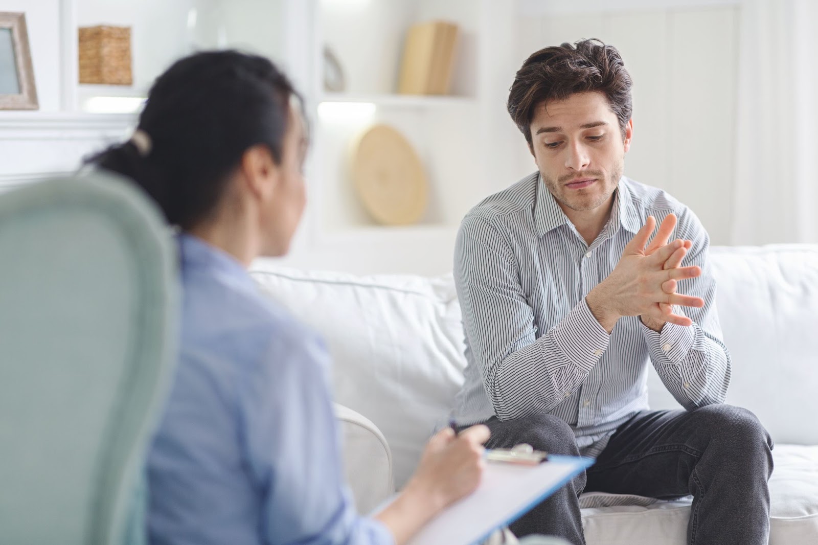 A man receiving TMS therapy while talking to a woman on a couch.