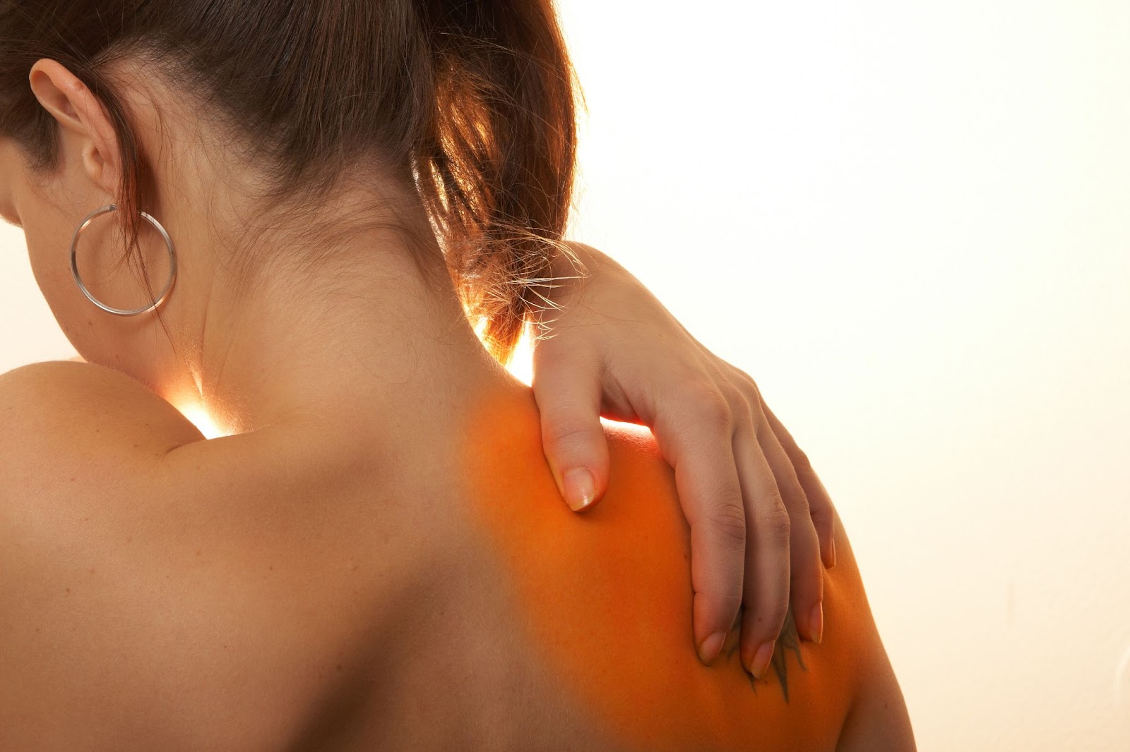 A woman with back pain holds her arm up, seeking relief through TMS therapy for pain management.