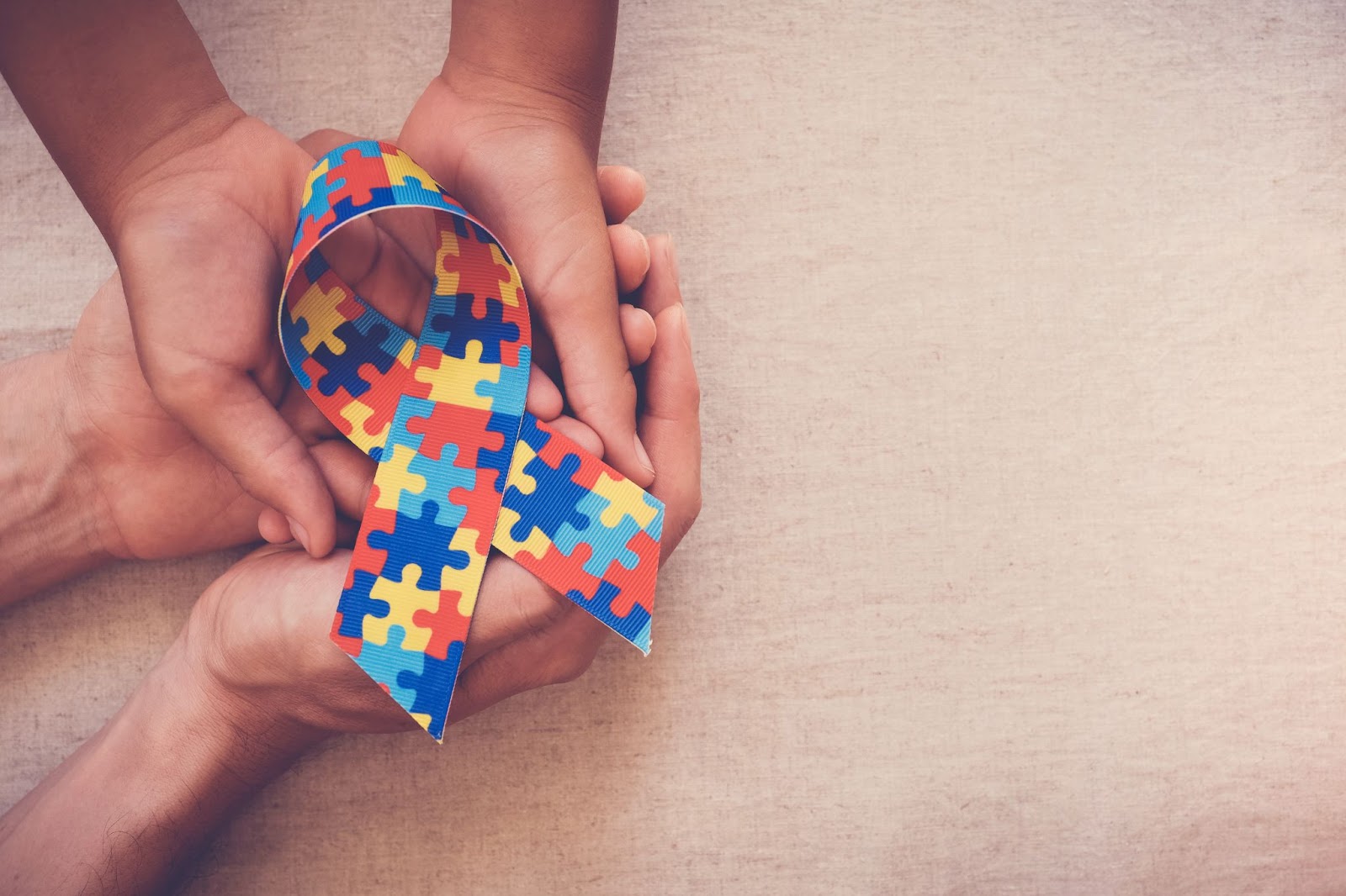 Hands holding a colorful autism ribbon for TMS therapy and autism spectrum disorder.