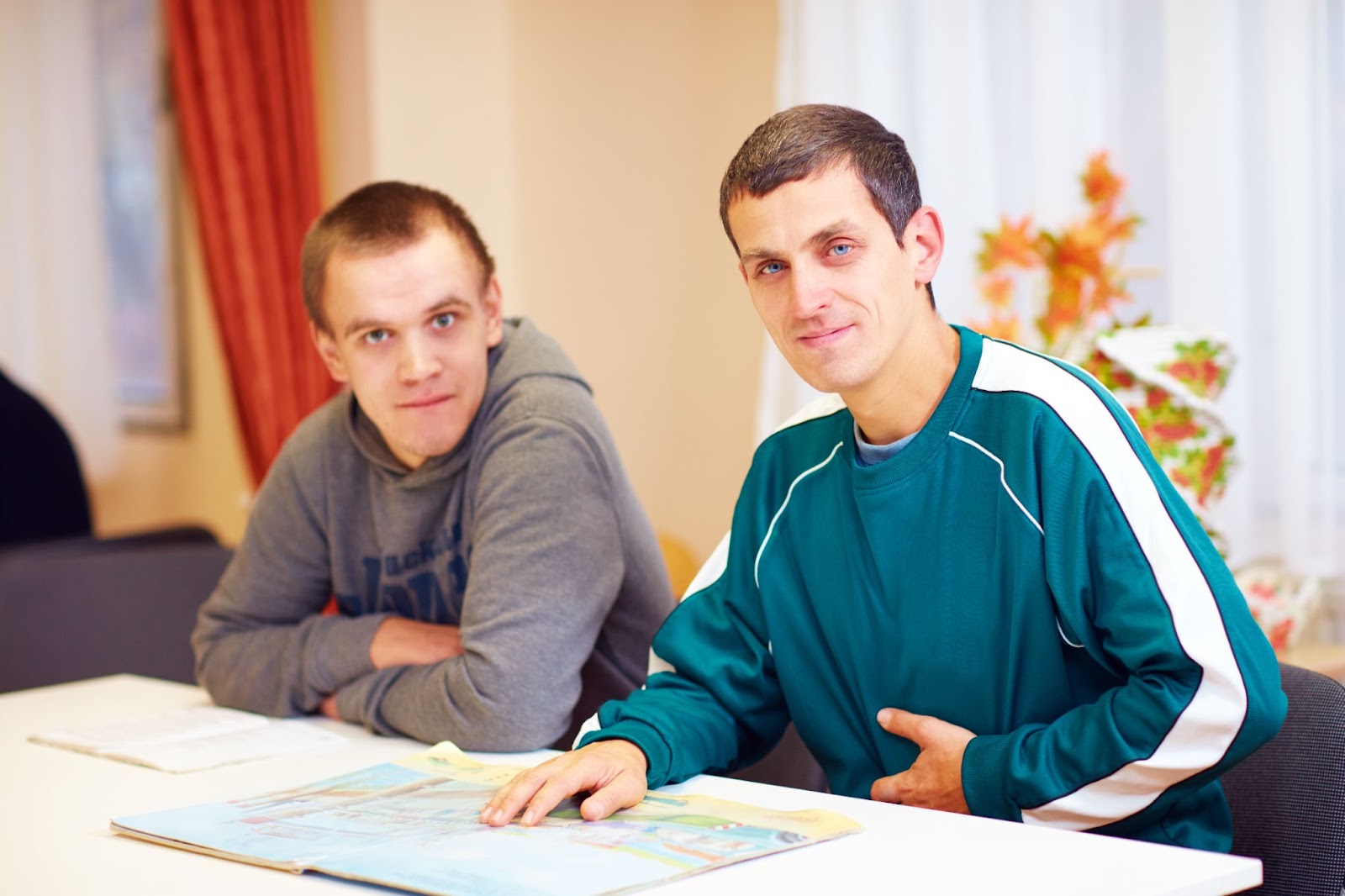 Two men sitting at a table discussing TMS therapy for autism spectrum disorder.