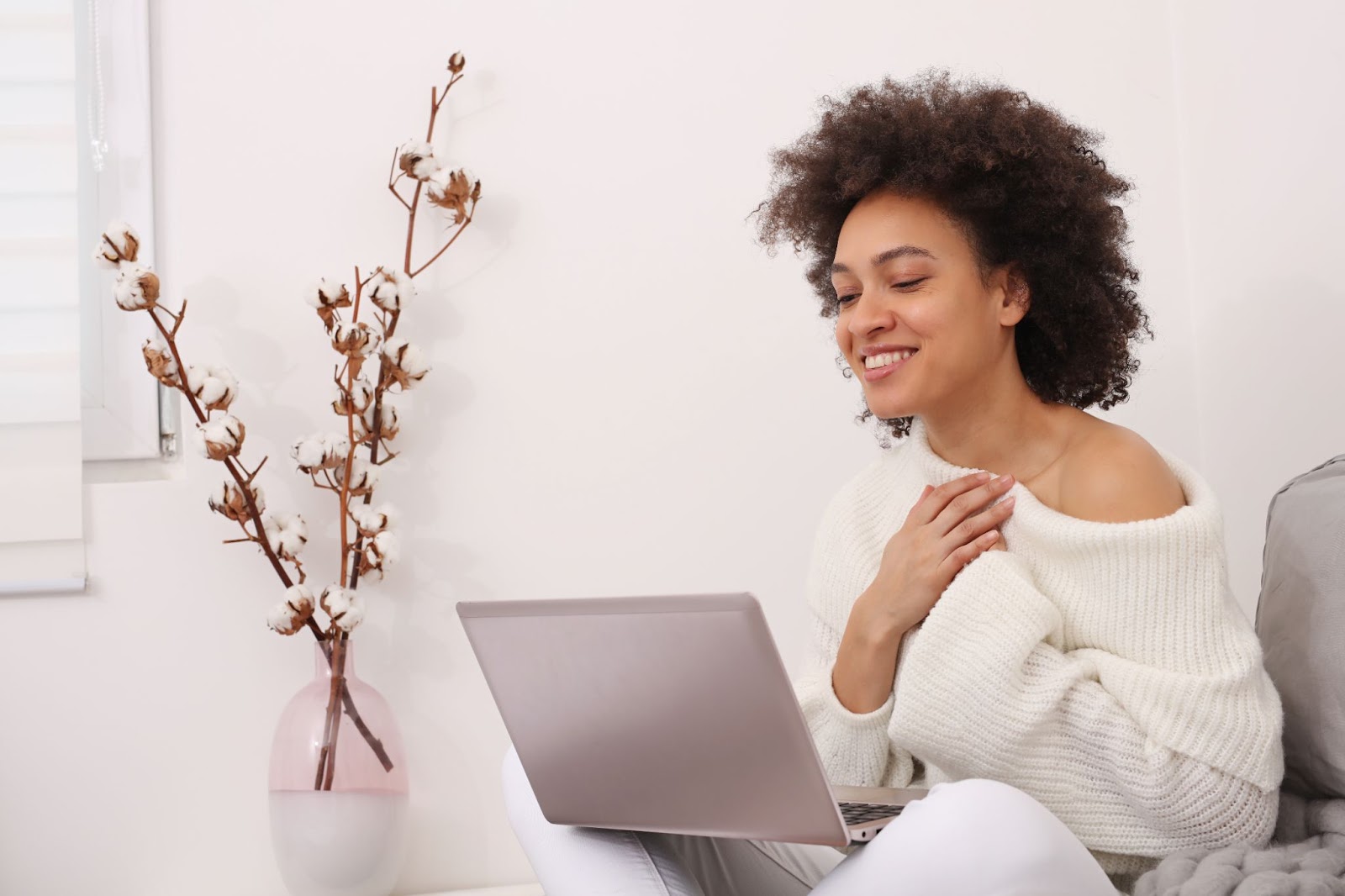 A woman seated on a couch, focused on her laptop, symbolizing the journey through TMS therapy for anxiety and depression.