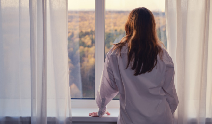 Rear view of a person looking pensively out a window.