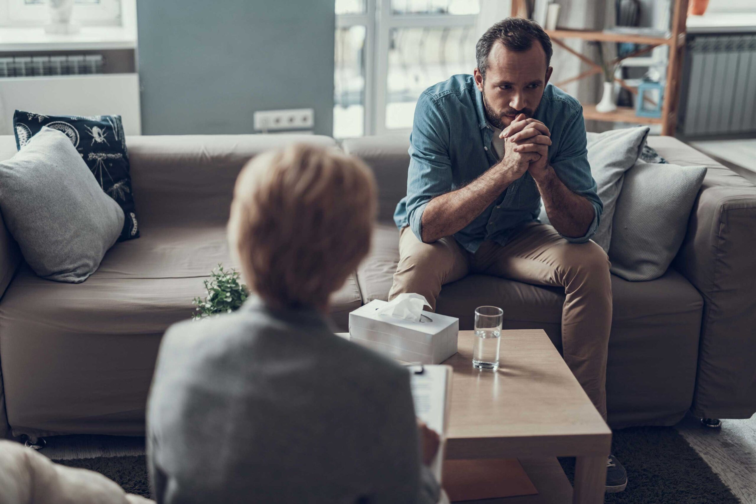 Rear view of a person looking pensively out a window.